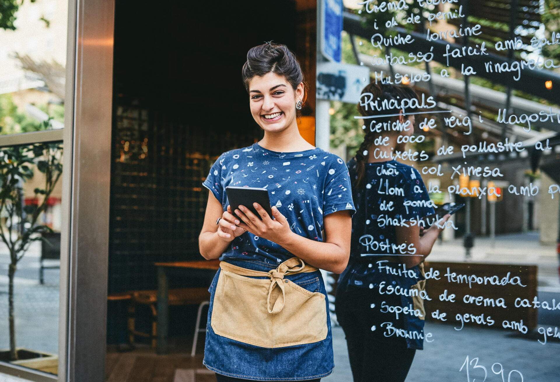 Eine Frau mit einem Tablet steht vor einem Restaurant